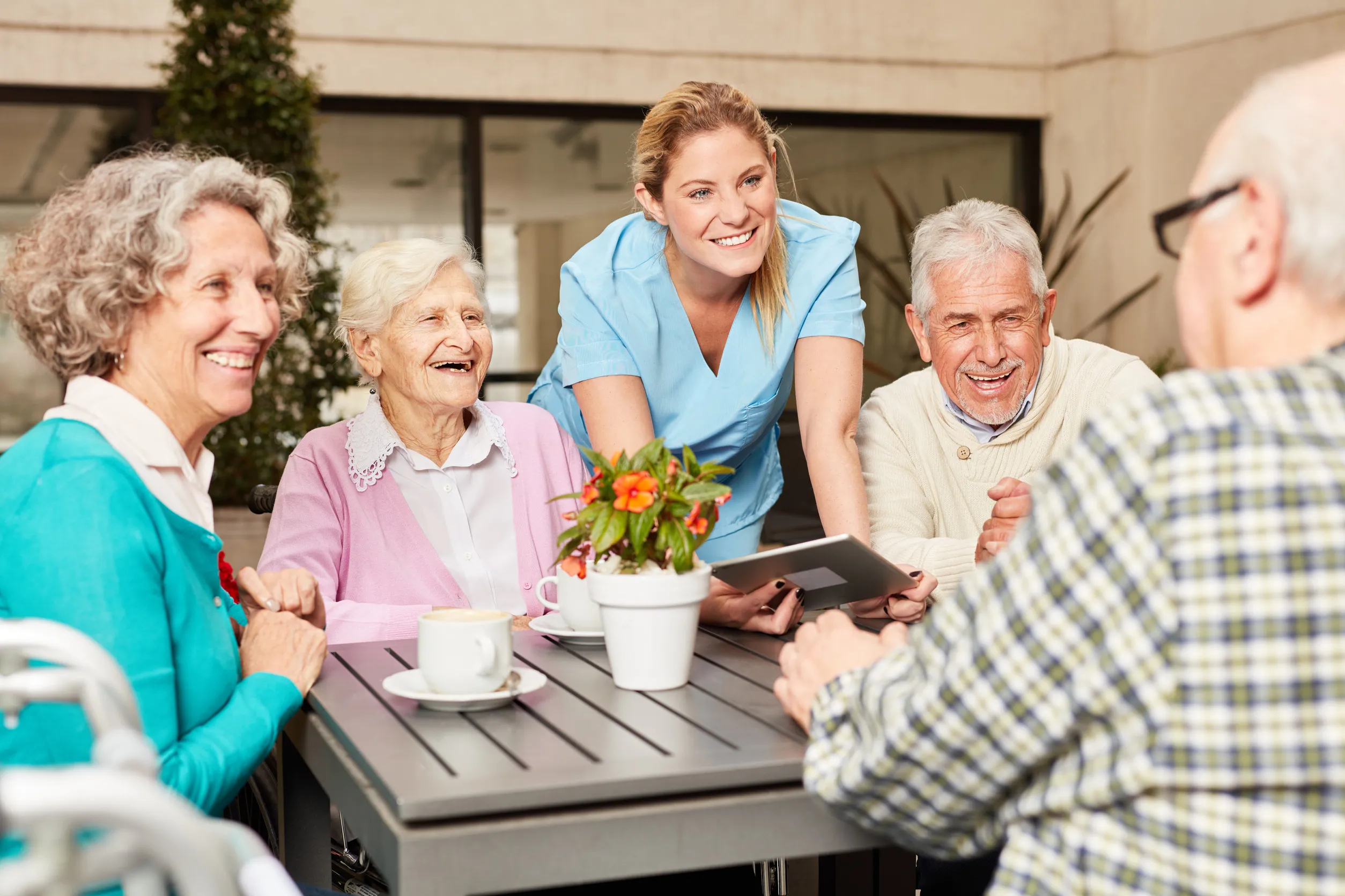 Group of seniors and caregiver using tablet computer while having coffee Group of seniors and caregiver using tablet computer while having coffee