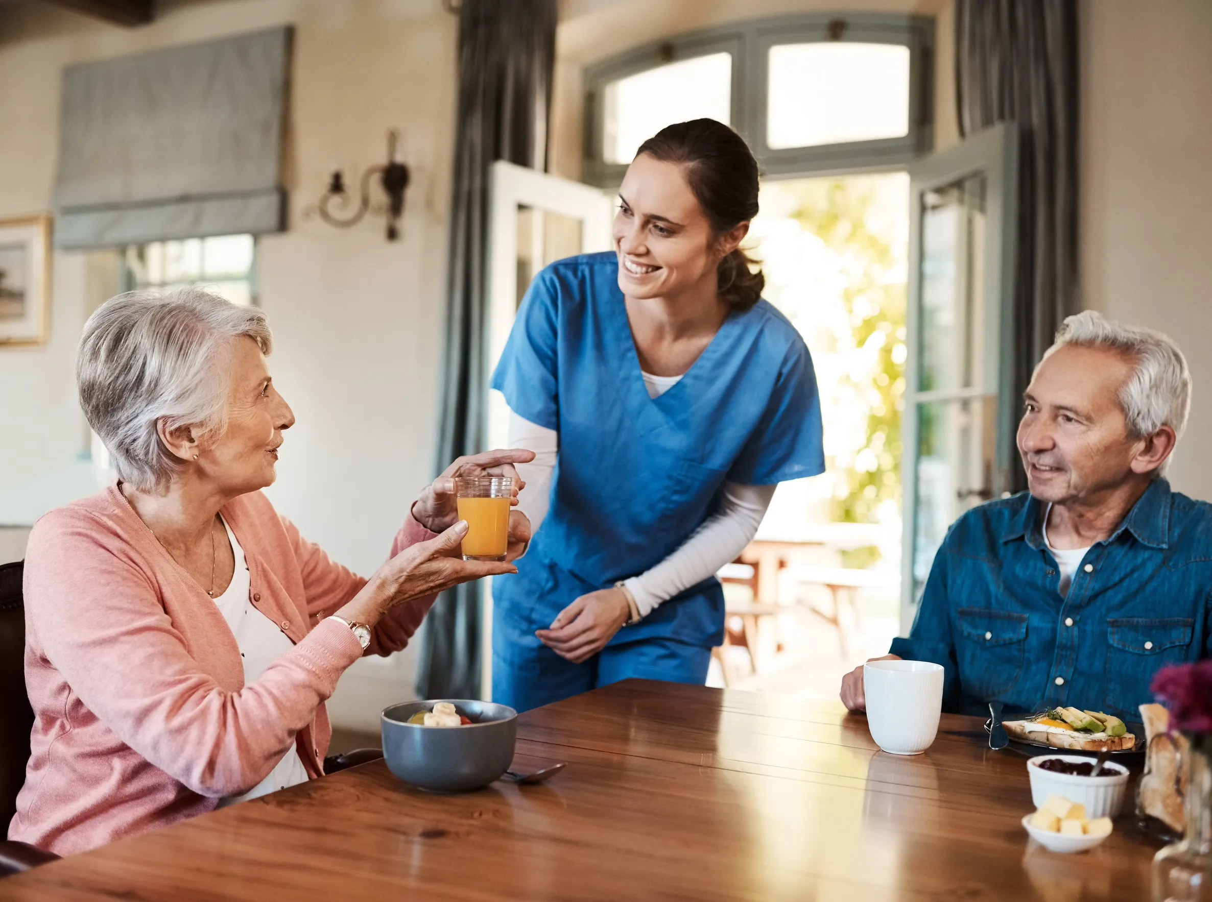 Happy, talking and caregiver with elderly patients for fruit drink in retirement home Happy, talking and caregiver with elderly patients for fruit drink in retirement home